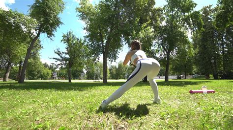 Young Female Athlete Doing Squat Exercises Outdoors In Park Fit Girl
