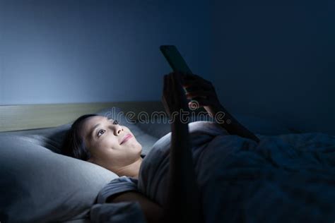 Mulher Que Olha No Telefone Celular E Que Encontra Se Na Cama Na Noite
