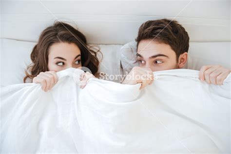 Funny Young Couple Lying And Hiding Under The Blanket In Bed Royalty Free Stock Image Storyblocks