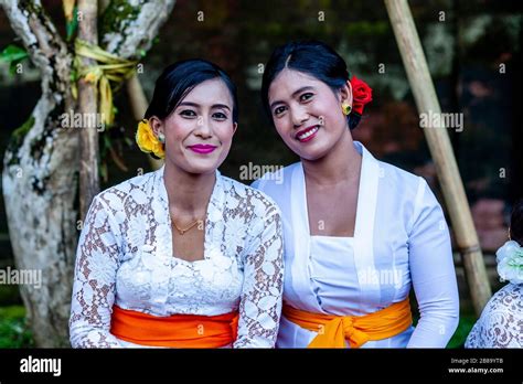 two balinese women in traditional dress pose for a photo at a hindu festival tirta empul water