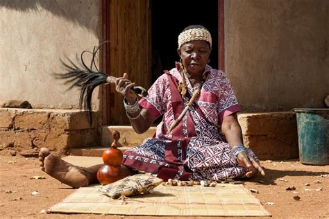 An Old Woman Sitting On The Ground With A Bird In Her Hand And Other