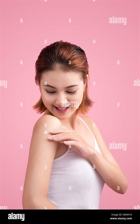 Woman Use Body Lotion On Arms And Touching Her Skin On Pink Background