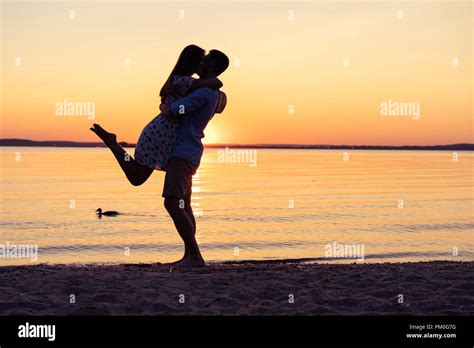 Silhouette Of Happy Couple On Beach At Sunset Man Taking The Girl In
