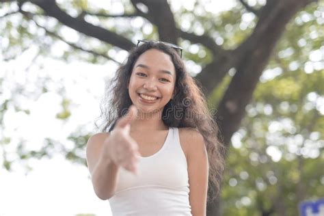 A Low Angle Photo Of A Smiling Asian Lady Extending Her Hand As She