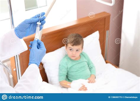 Doctor Adjusting Intravenous Drip For Little Child In Hospital Stock