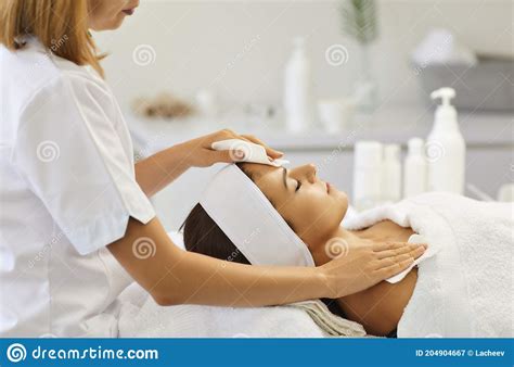 Cosmetologist Wiping Serene Womans Shoulders And Forehead After Facial Massage In Spa Salon