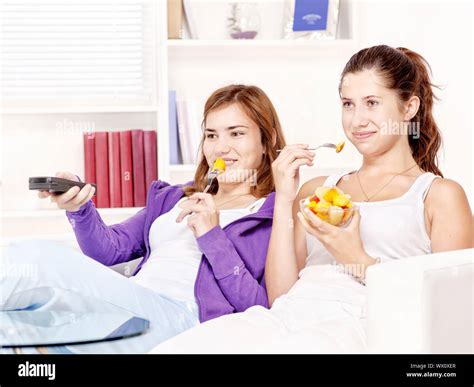 Las Adolescentes Viendo La Tv En El Sofá Y Comer Ensalada De Frutas Fotografía De Stock Alamy