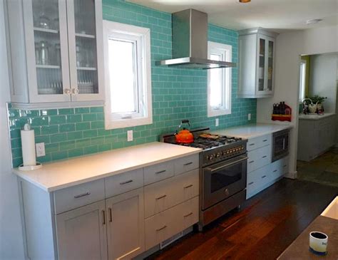 Modern kitchen remodel with turquoise glass tile, no upper cabinets gray and white kitchen design with shaker cabinets, gray glass subway tile backsplash, gray glass herringbone tile accent, custom white barrel range hood, thermador range, cambria quartz countertop, under cabinet lighting. Reader Renovation! | House of Turquoise