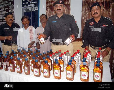 Police Officers Show Seized Liquor Bottles Which Were Allegedly Recovered From Possession Of