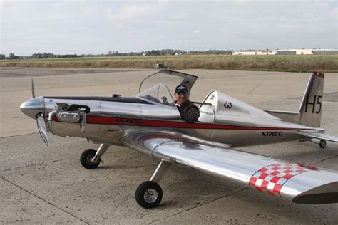 a small silver airplane sitting on top of an airport tarmac with a man