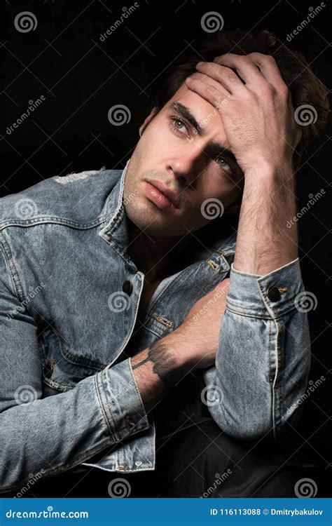 Portrait Of A Sad Brooding Young Man On Black Background Stock Photo