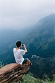 "Man Sitting On The Edge Of A Cliff Taking A Photo" by Stocksy ...