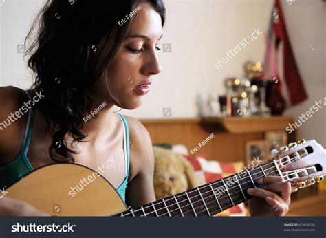Young Beautiful Woman Playing Guitar In Her Room Stock