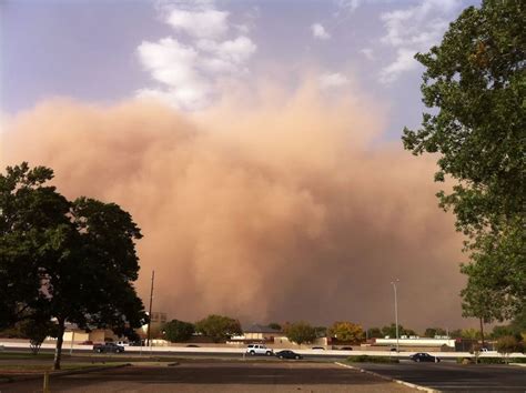 A Large Dust Cloud Looms In The Sky Over A Parking Lot