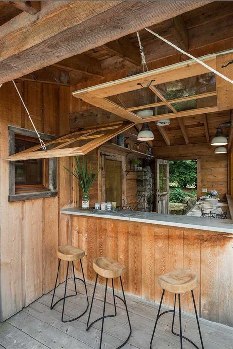 An Outdoor Bar With Three Stools In Front Of It And Wood Paneling On