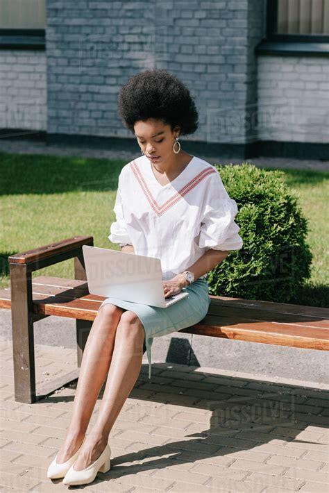 Beautiful African American Businesswoman Sitting On Bench And Using