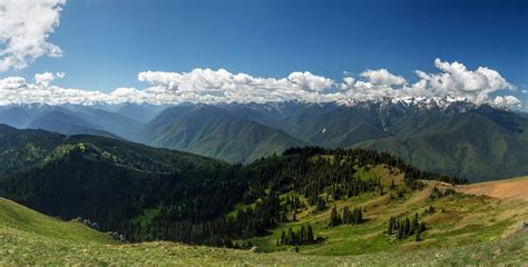 Green Mountains With Snow Topped Crests Under Fluffy Clouds Snow On