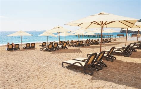 Free Photo Scenic View Of Private Sandy Beach With Sun Beds From The Sea And The Mountains