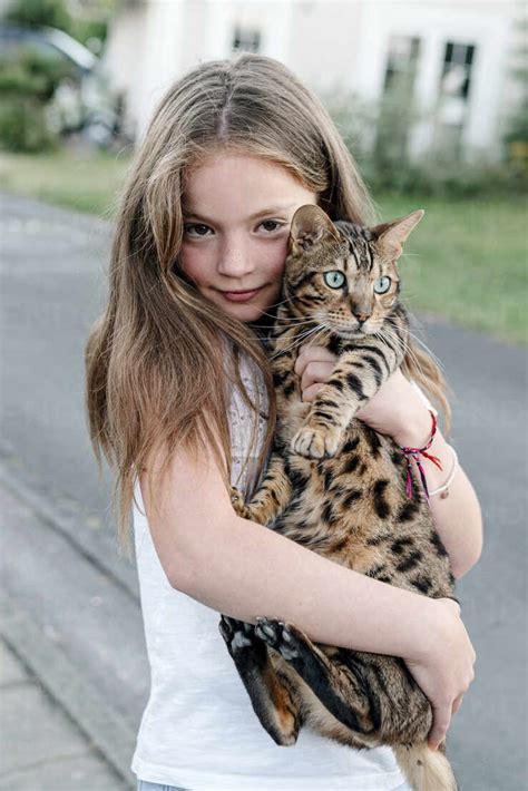 Girl Carrying Domestic Cat While Standing On Street Stock Photo