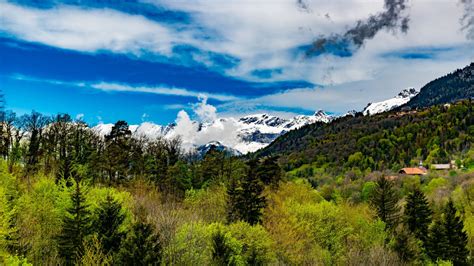 Landscape View Of White Covered Mountains Trees Under Blue Cloudy Sky