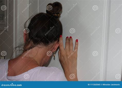 woman ear pressed to the door with listening what is happening in the next room stock image