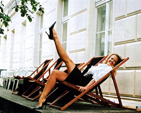 A Woman Sitting In A Chair With Her Legs Up On The Ground Next To Some Chairs
