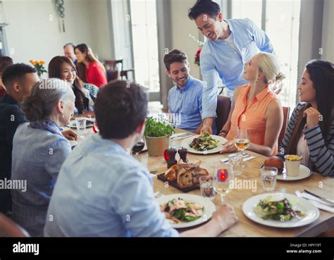 Waiter Serving Food To Friends Dining At Restaurant Table Stock Photo