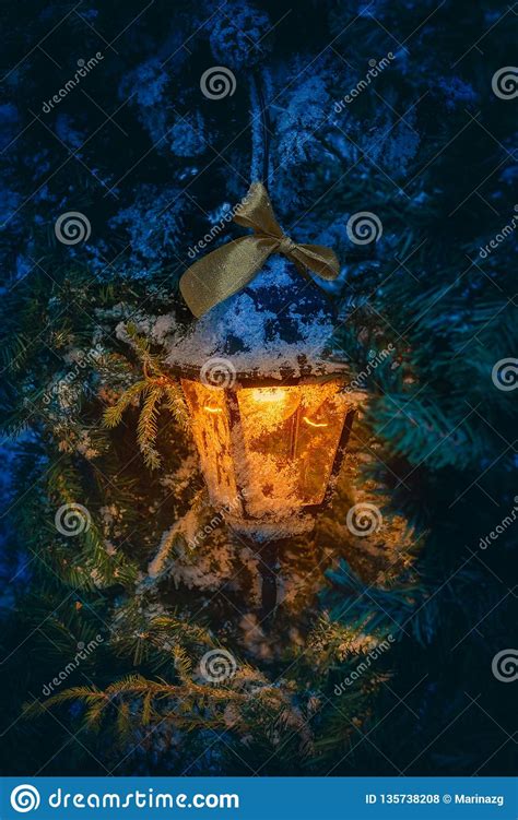 Lantern With Orange Light Glowing Inside Hanging From The Fir Tree