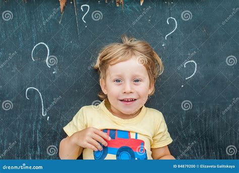 Top View Of A Little Blond Kid Boy With Question Mark On Blackboard