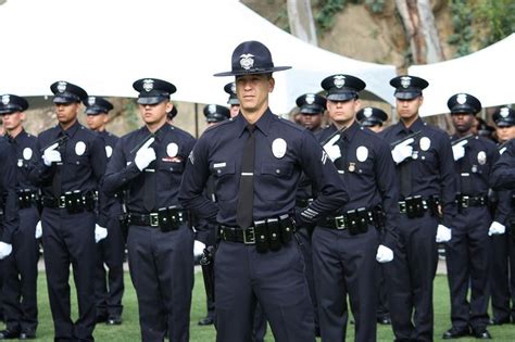 A Group Of Police Officers Standing Next To Each Other On The Grass In
