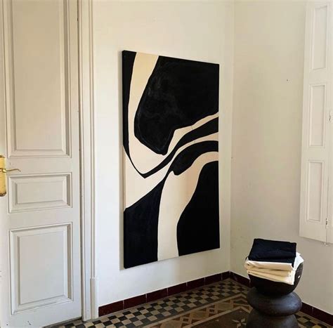 A Black And White Painting Hanging On The Wall Next To A Chair In A Room