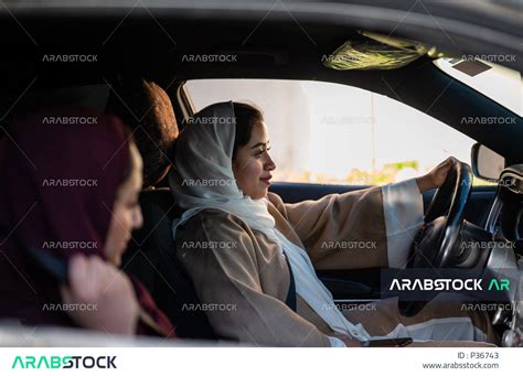 امراة عربية خليجية سعودية مستمتعة بقيادة السيارة و بجانبها سيدة خليجية سعودية ،خدمة توصيل الركاب