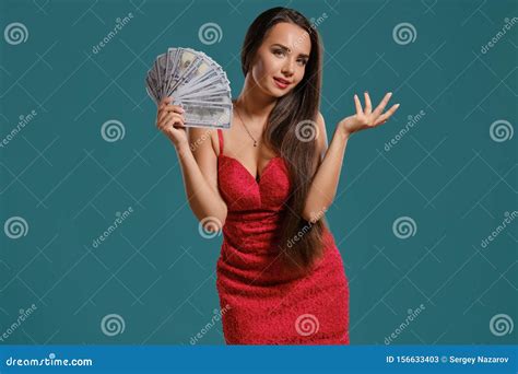 Brunette Girl With A Long Hair Wearing A Red Dress Is Posing Holding A Fan Of Hundred Dollar