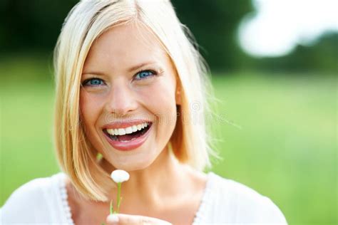 She Loves A Good Laugh Happy Young Woman Holding A Tiny Flower Outdoors And Laughing Stock