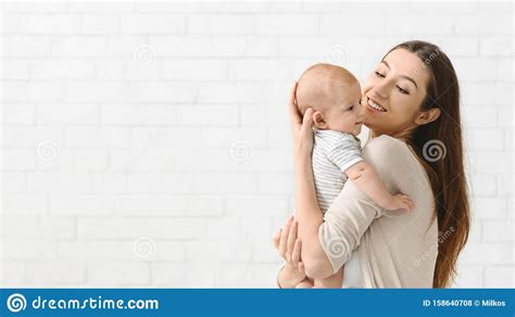 Mother Cuddling Her Newborn Son At Home Enjoying Time Together Stock
