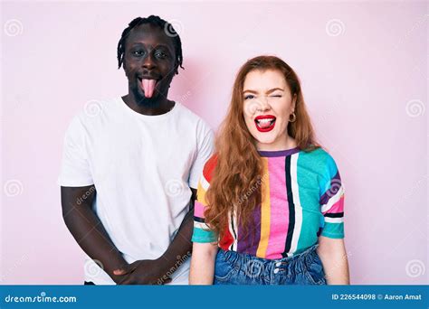 Interracial Couple Wearing Casual Clothes Sticking Tongue Out Happy With Funny Expression Stock