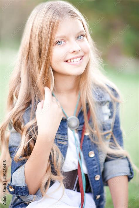 smiling blonde teen girl 15 16 year old posing outdoors looking at camera spring season stock