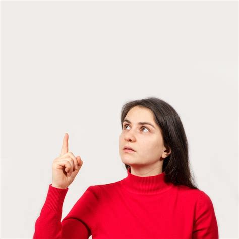 Premium Photo A Brunette Woman In Red Looks Up And Points Her Finger