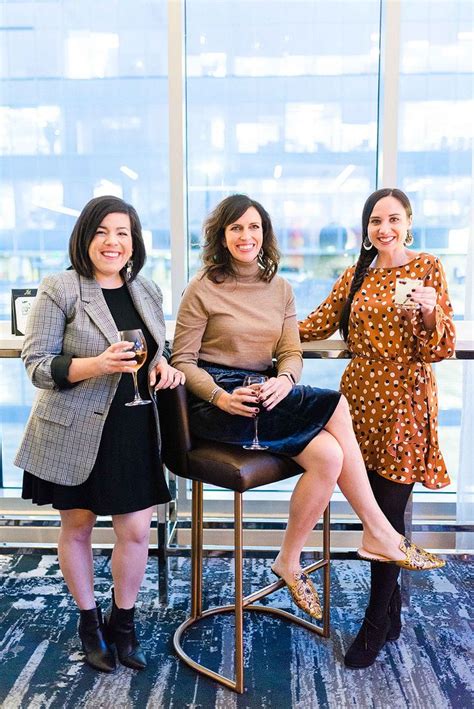 three women sitting on chairs holding wine glasses in their hands and smiling at the camera