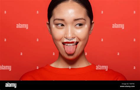 Close Up Of Young Asian Woman Sticking Out Tongue And Looking Away