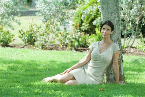 Woman Sitting On The Ground Under Tree Smiling Looking Up Stock