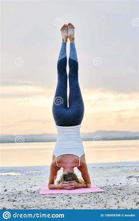 Woman Doing Hatha Yoga Headstand Or Sirsasana On Nature Rear View Stock
