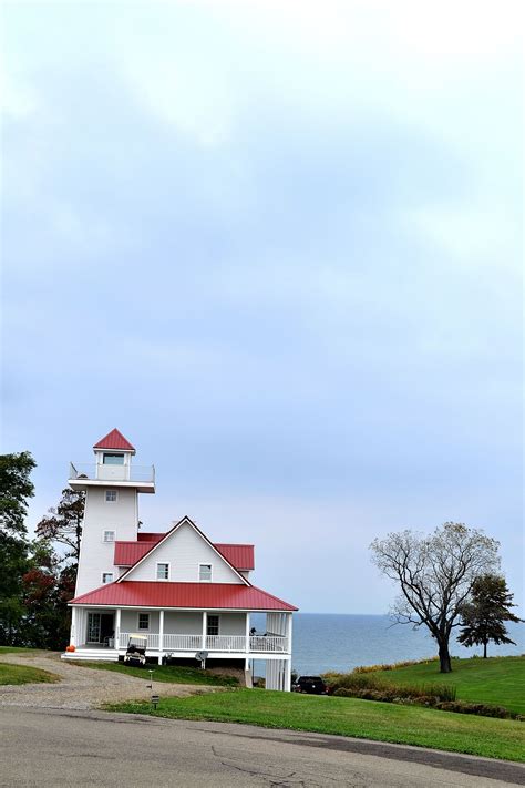 A White House With A Red Roof Next To The Ocean