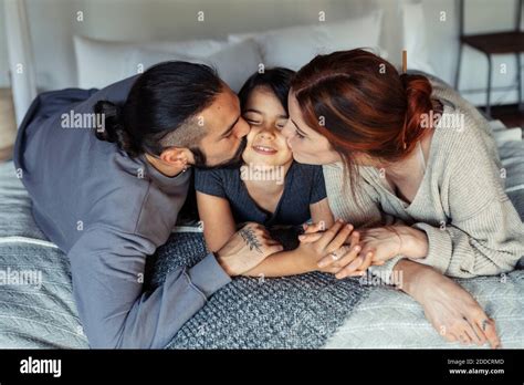 Mère Et Père Embrassant La Fille Tout En étant Allongé Sur Le Lit à