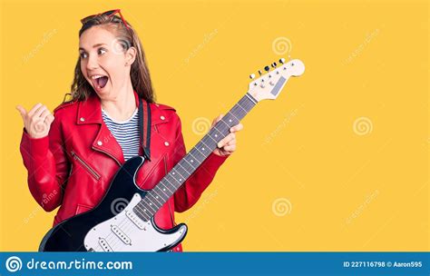 Young Beautiful Blonde Woman Playing Electric Guitar Pointing Thumb Up