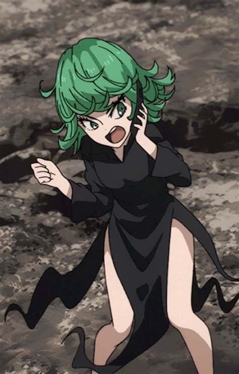A Woman With Green Hair And Black Dress Walking Across A Rocky Area In