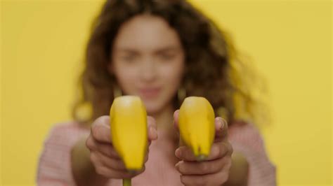 Playful Girl Having Fun With Banana On Yellow Background Portrait Of