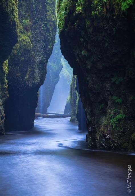 A Narrow River Surrounded By Tall Rocks And Greenery On Both Sides With