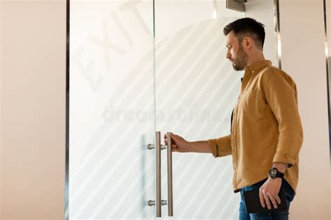 Confident Businessman Opening Glass Door Entering Modern Office Holding
