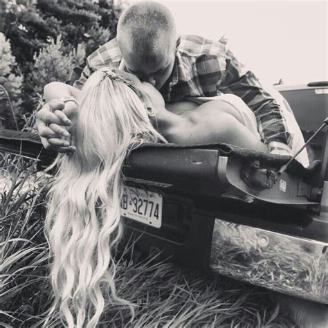 A Man And Woman Kissing In The Back Of A Pick Up Truck With Long Blonde